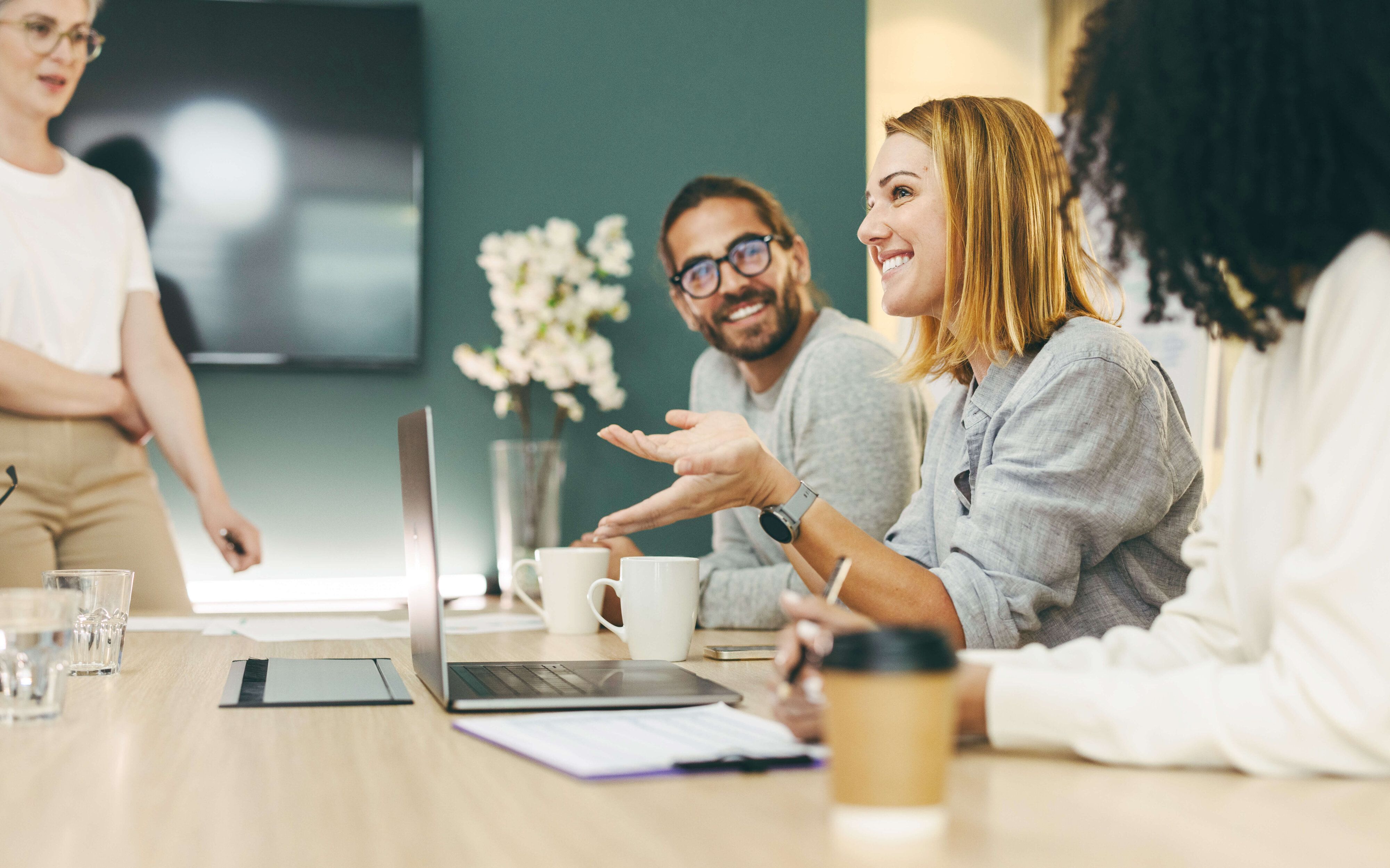 Vier zufriedene Personen an einem Schreibtisch im Gespräch