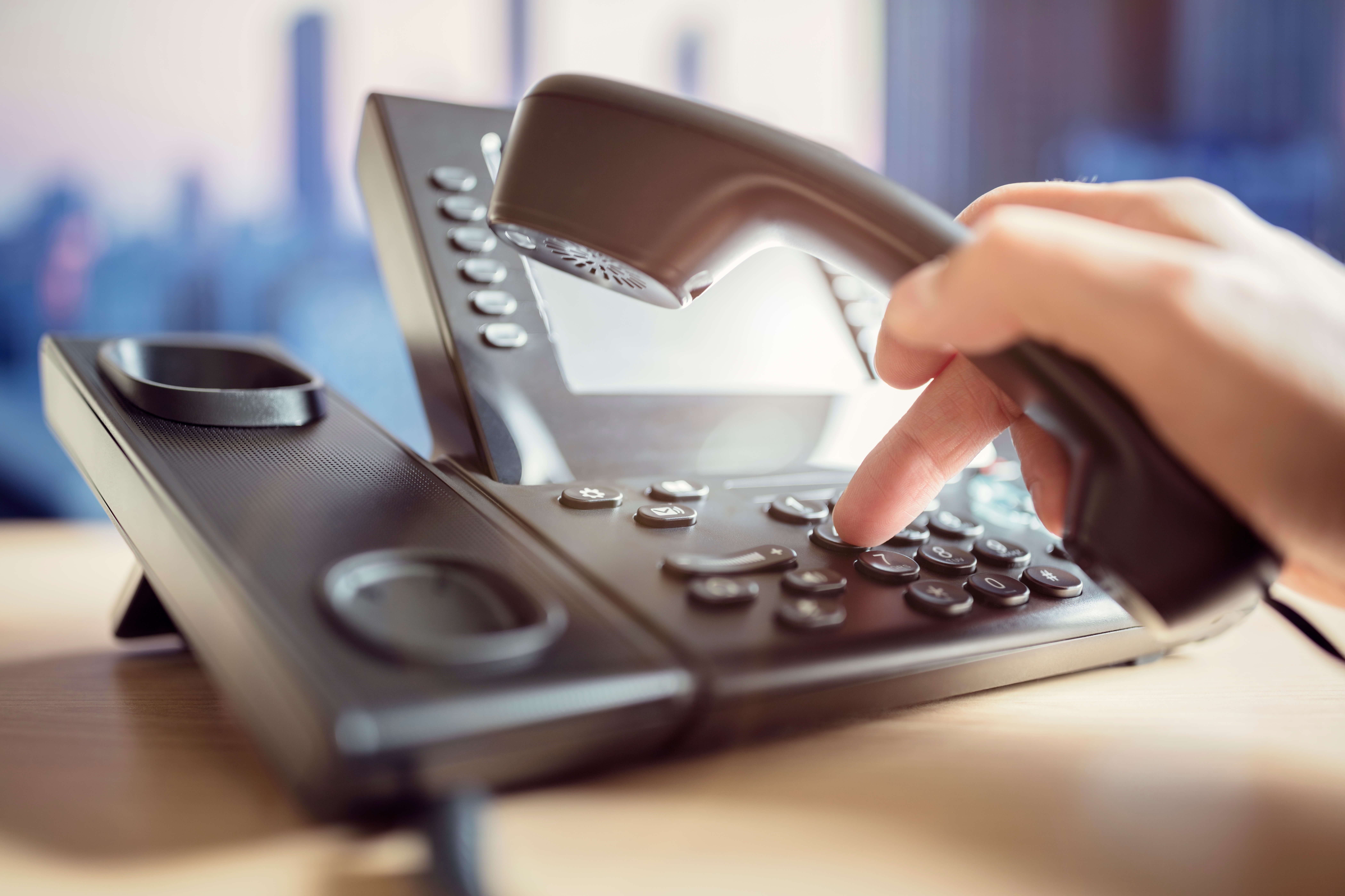 Une personne compose un numéro sur le téléphone fixe de Green