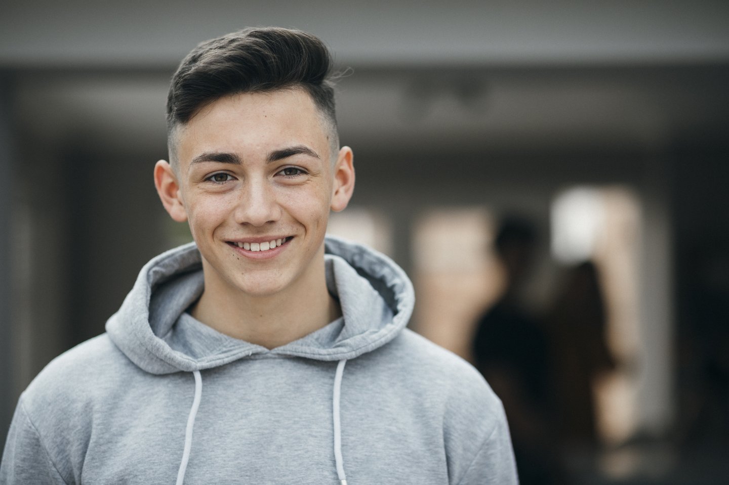 Lachender Lernender mit grauem Kaputzensweater