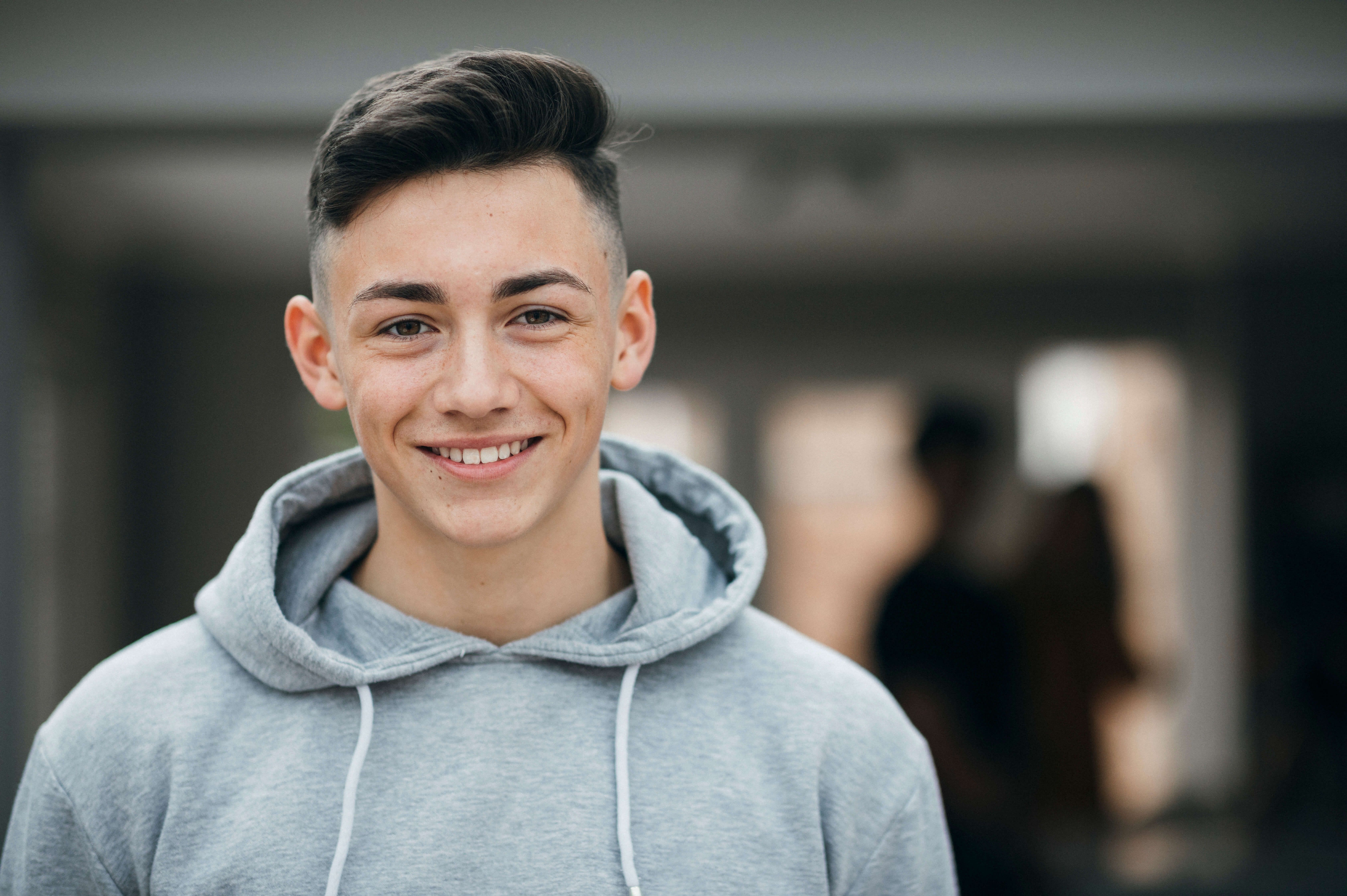 Lachender Lernender mit grauem Kaputzensweater