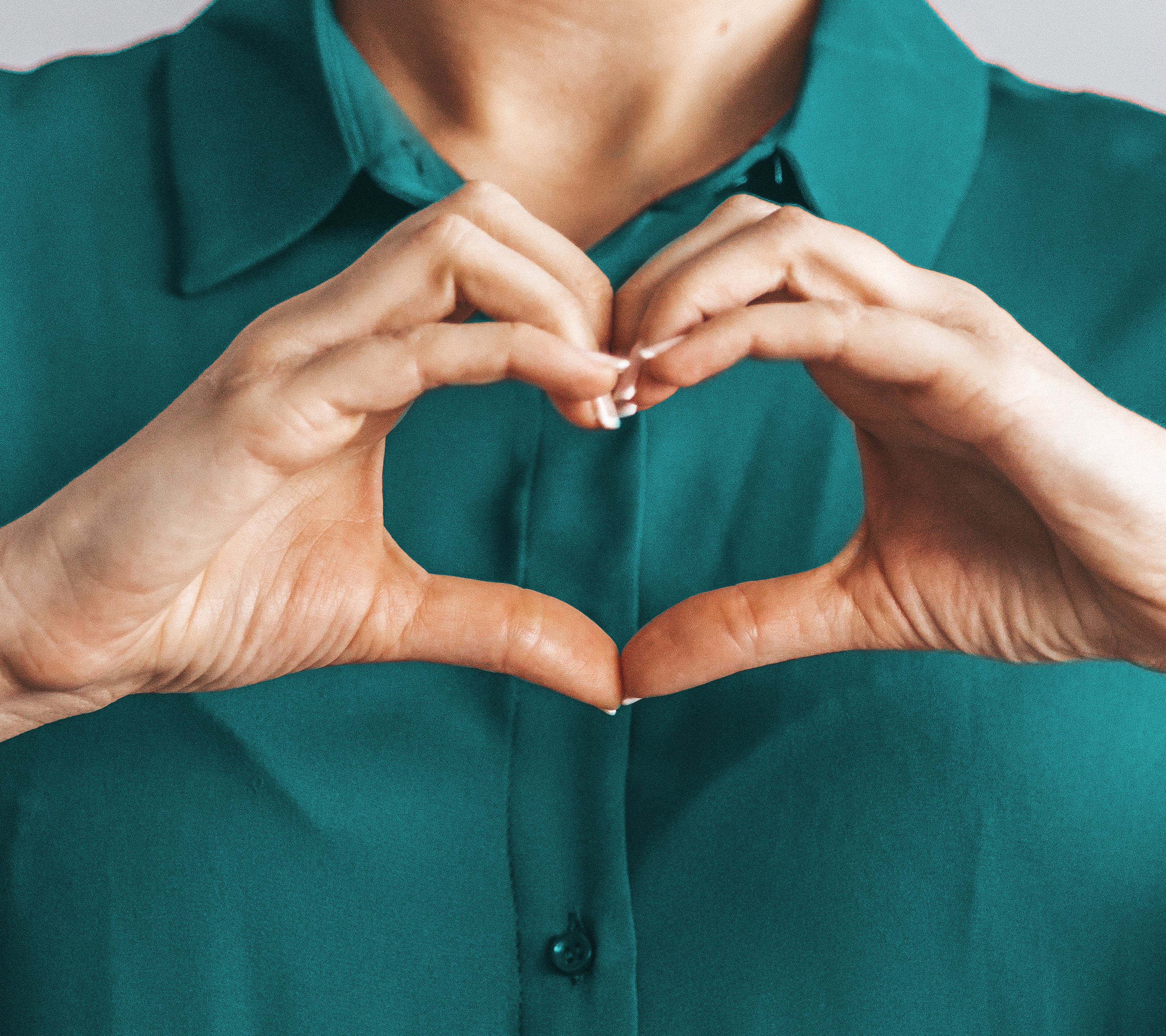 Frau mit Bluse macht Herz mit Händen