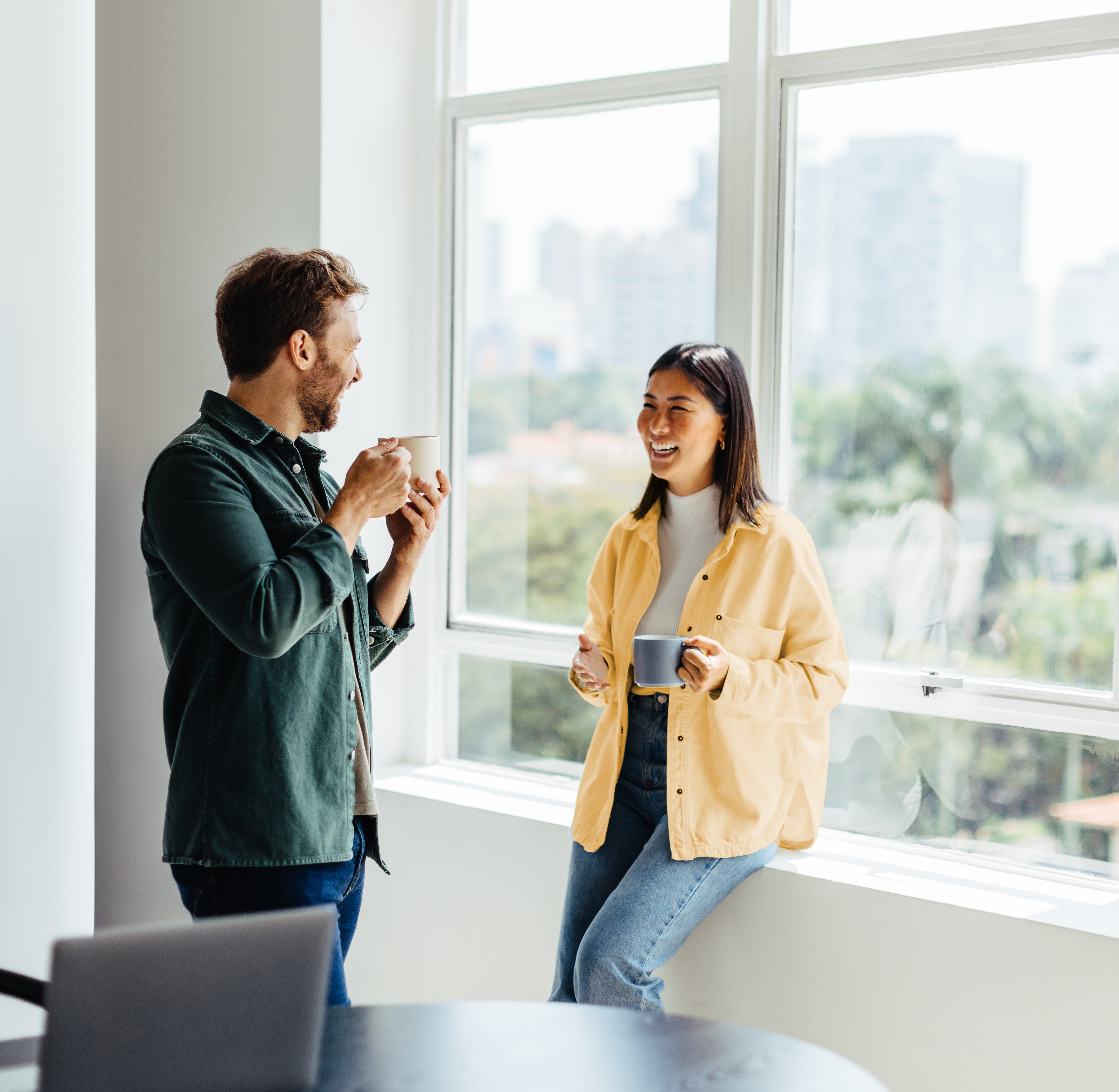 Zwei Mitarbeitende stehend mit Kaffee in der Hand in einem Gespräch