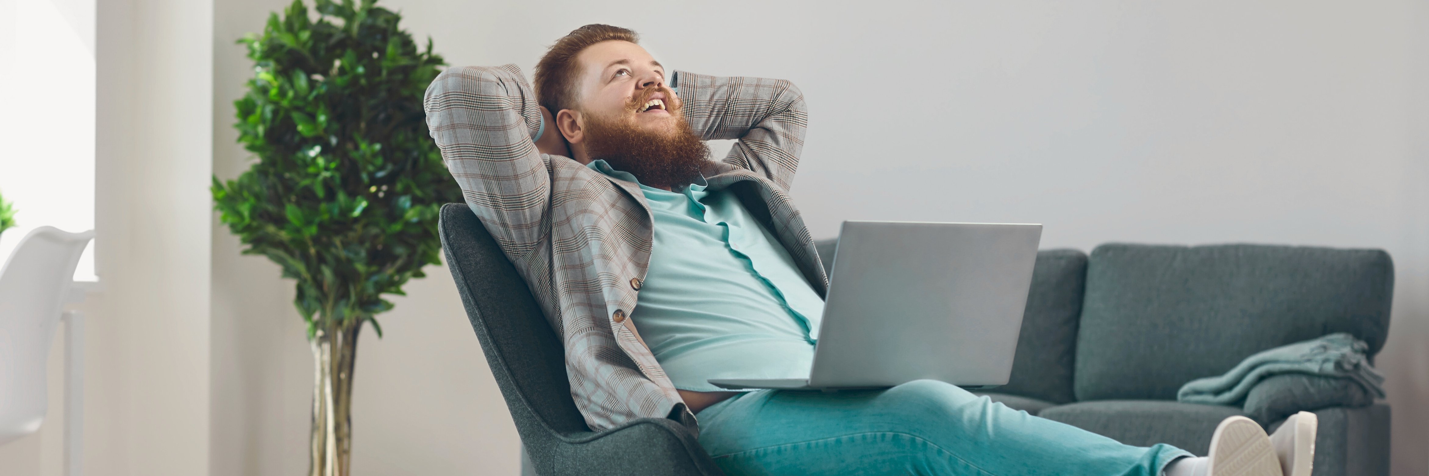 Mann entspannt mit Laptop auf dem Schoss im Wohnzimmer. Symbolbild für digitale Freiheit und persönliche Projekte
