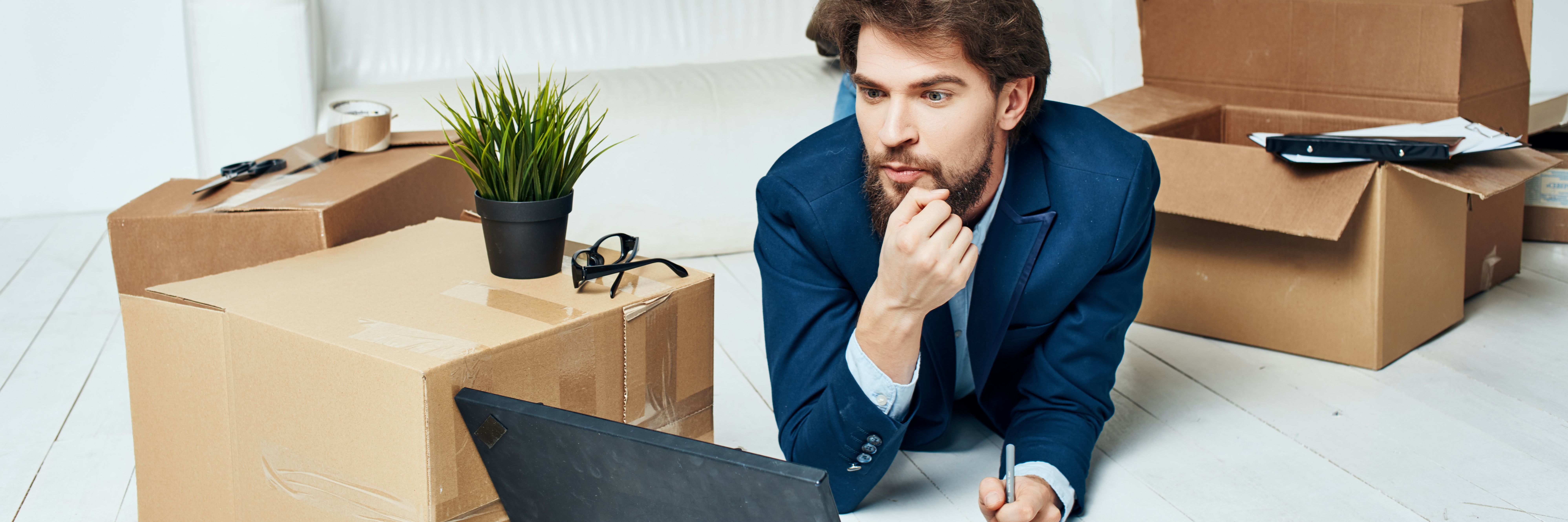 Man lies on the floor surrounded by moving boxes, thinking about how to quickly and securely transfer his domain to Green.