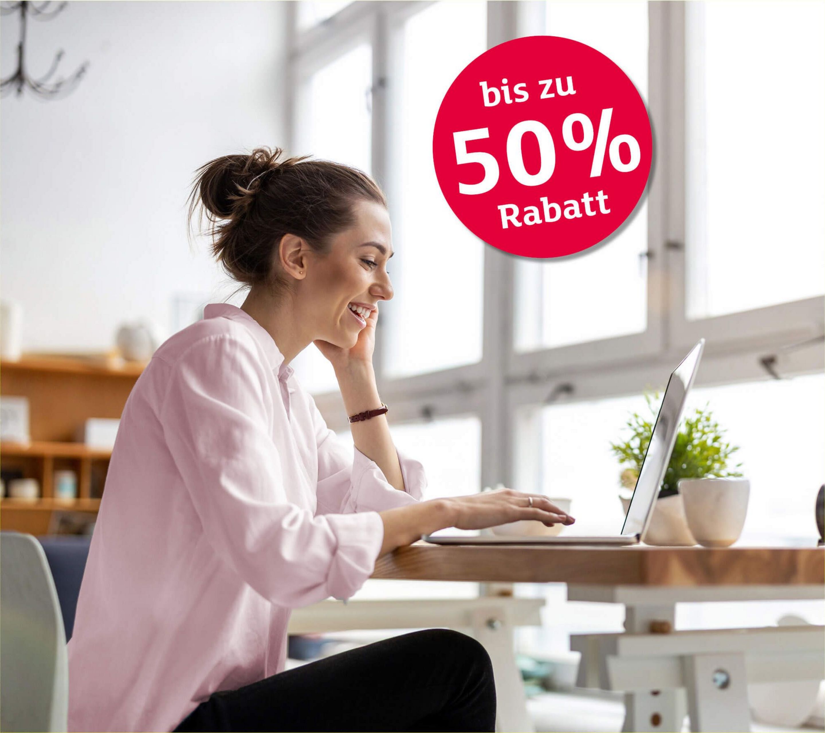 Glückliche junge Frau arbeitet an ihrem Esstisch am Laptop