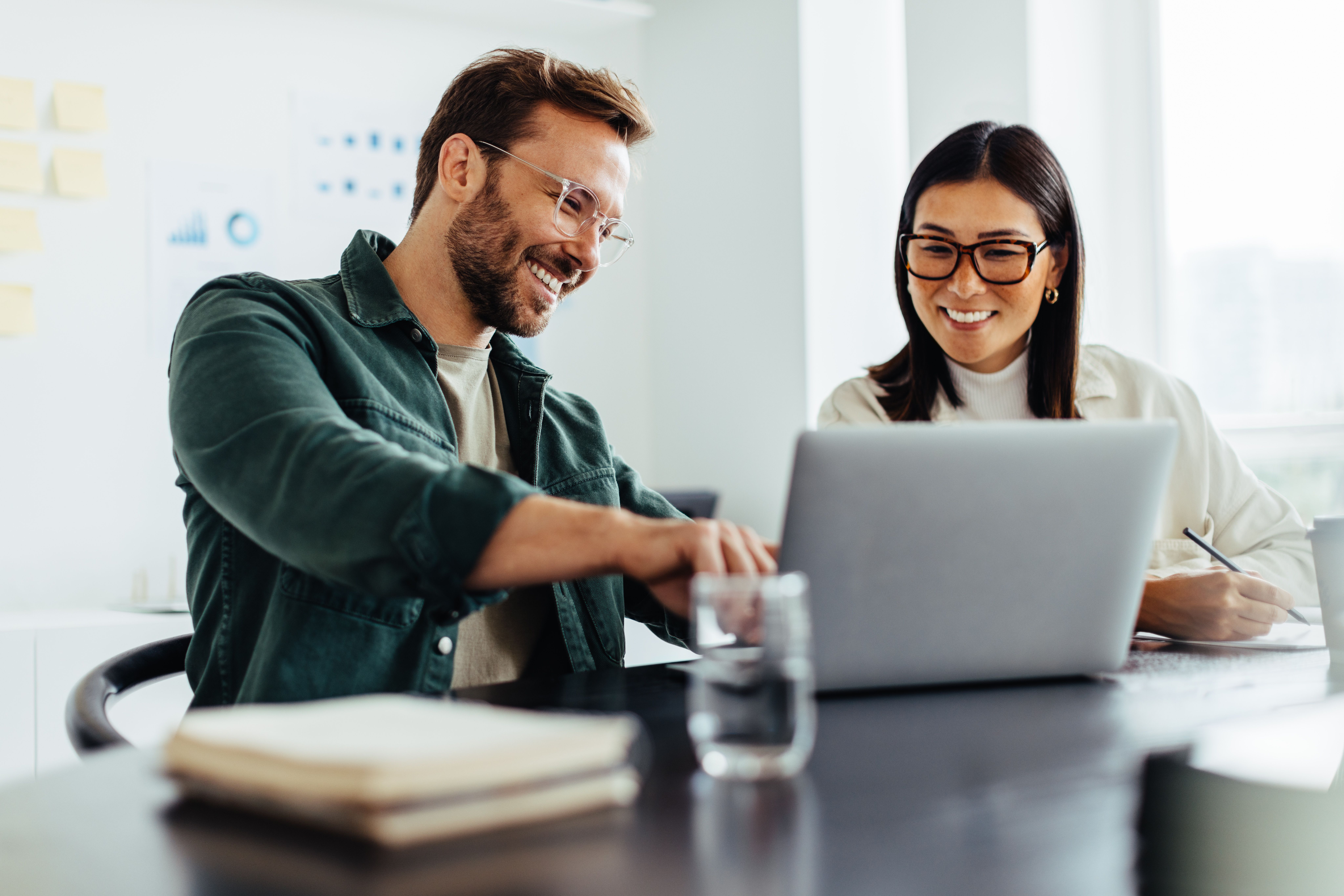 A man and a woman discussing something while pointing at a laptop.