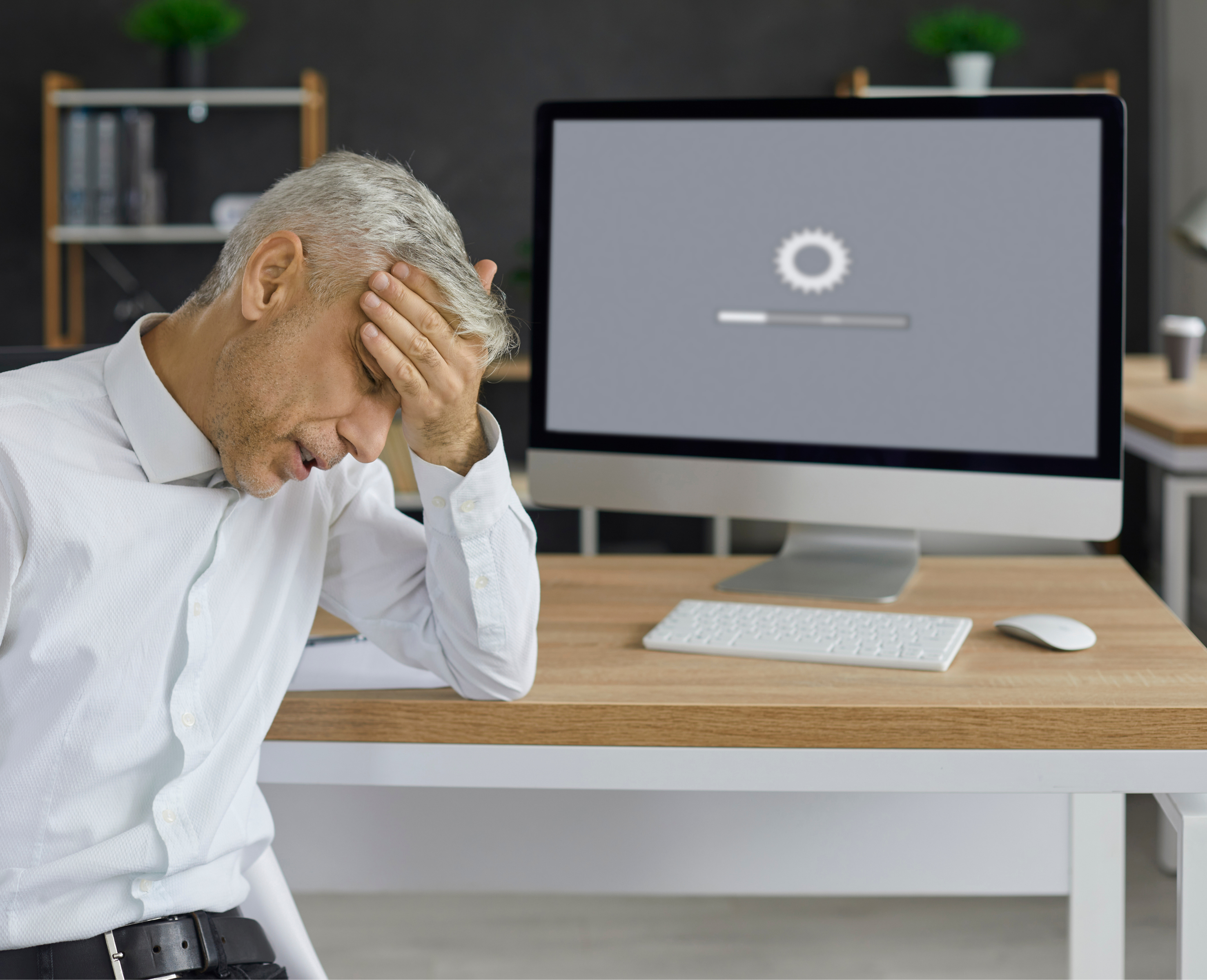 Mann im Büro mit Frustration vor einem Computer, der langsam lädt – Symbolbild für schlechte Website-Performance