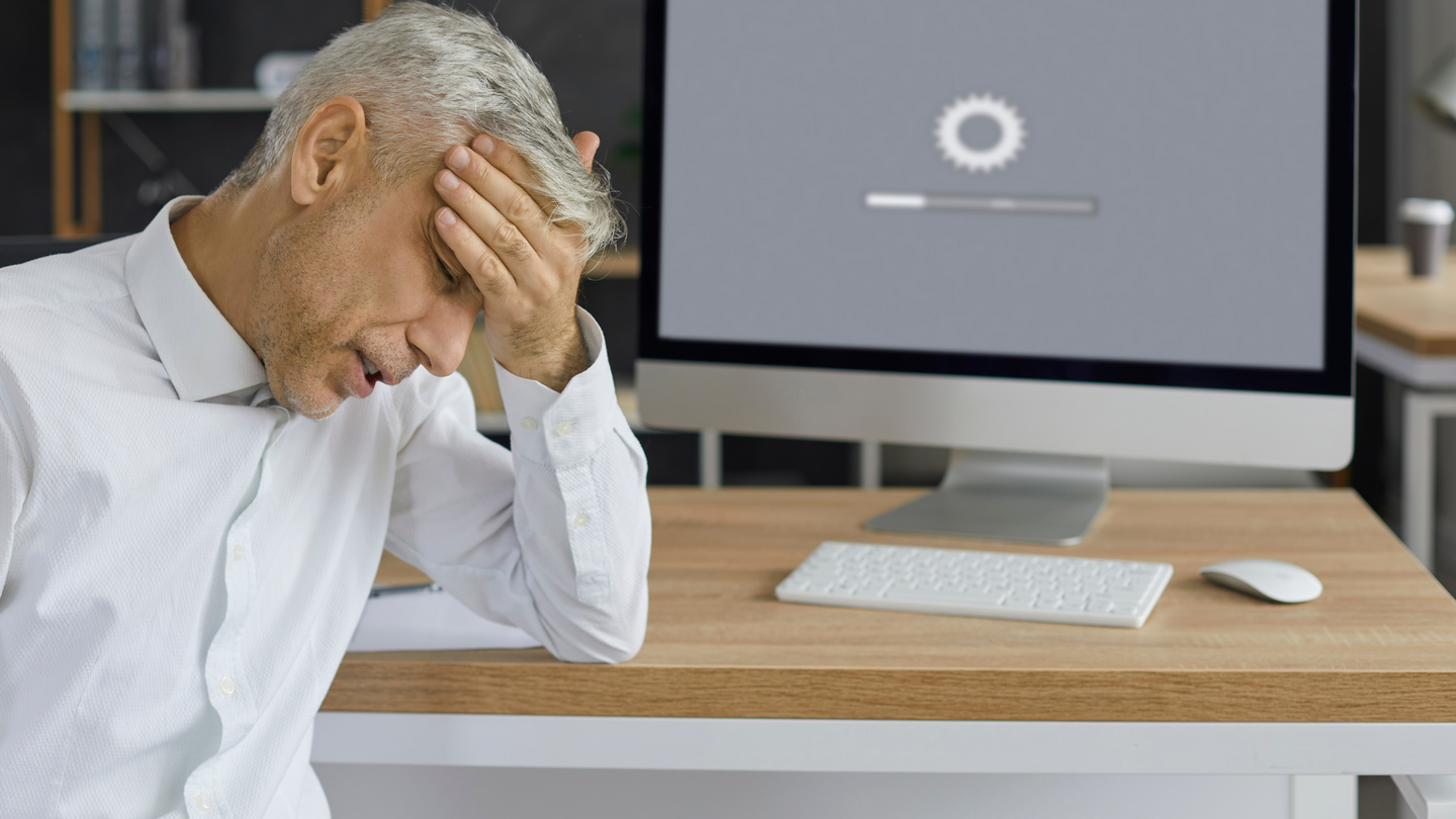 Mann im Büro mit Frustration vor einem Computer, der langsam lädt – Symbolbild für schlechte Website-Performance
