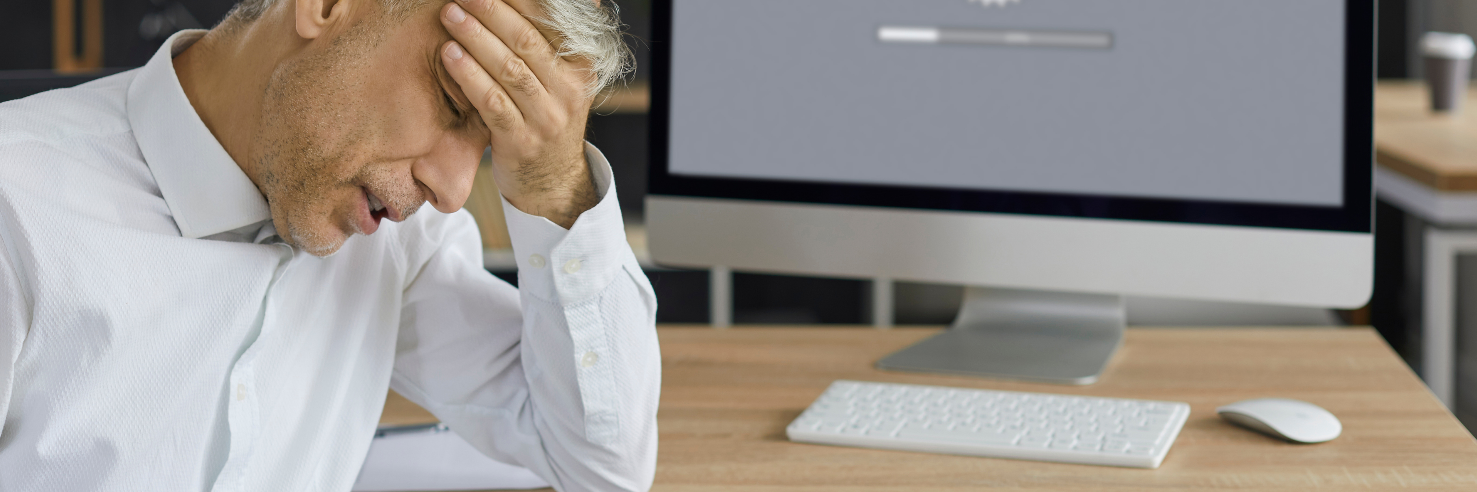 Frustrated man in an office sitting in front of a computer with a slow-loading screen – symbolic of poor website performance