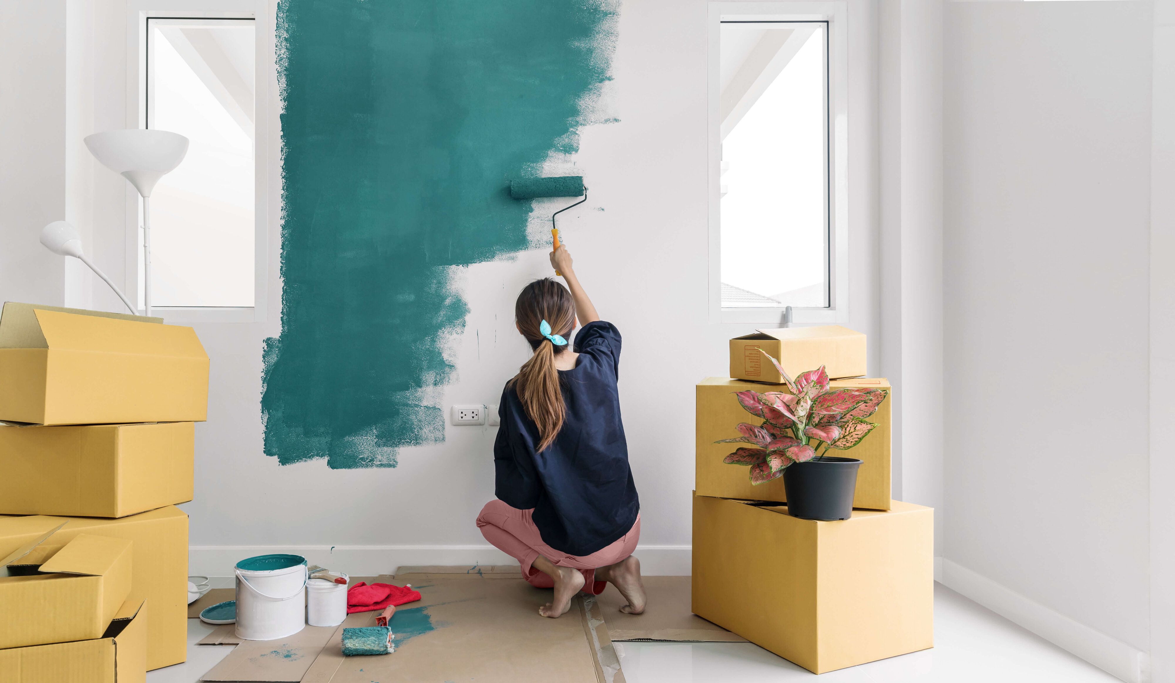Woman is moving and painting a wall in colors of Green