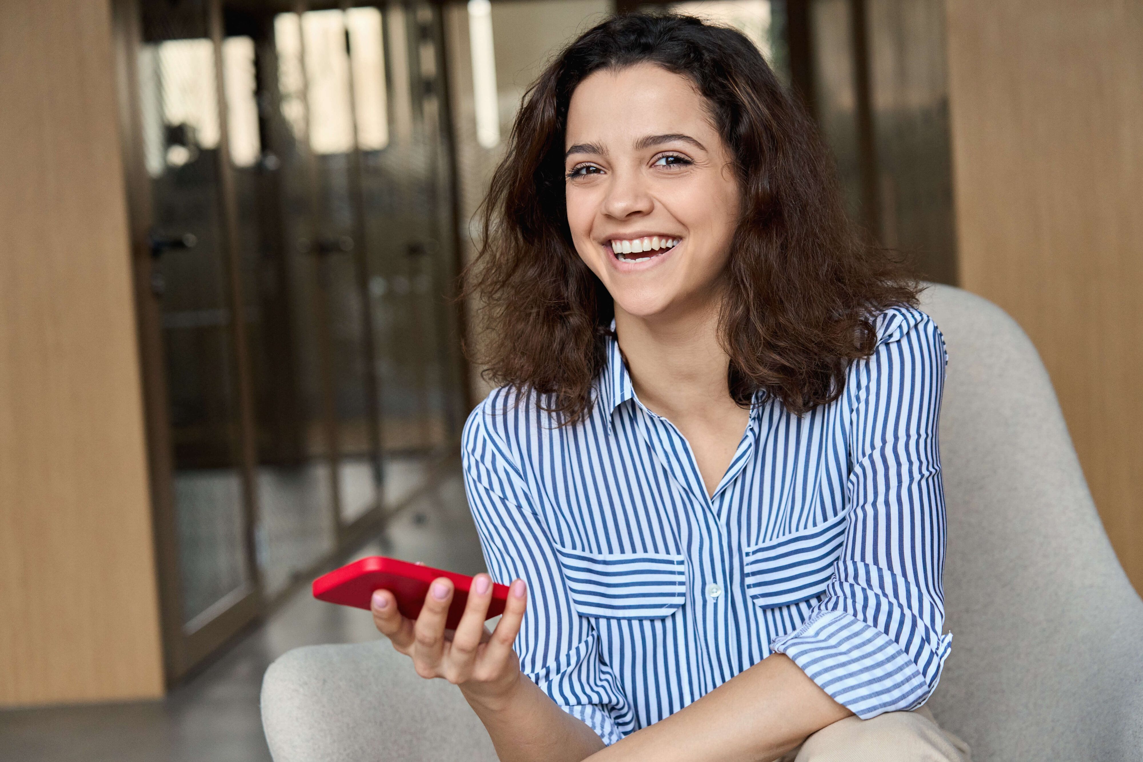 Lachendes, sitzendes Mädchen mit Mobile in der Hand