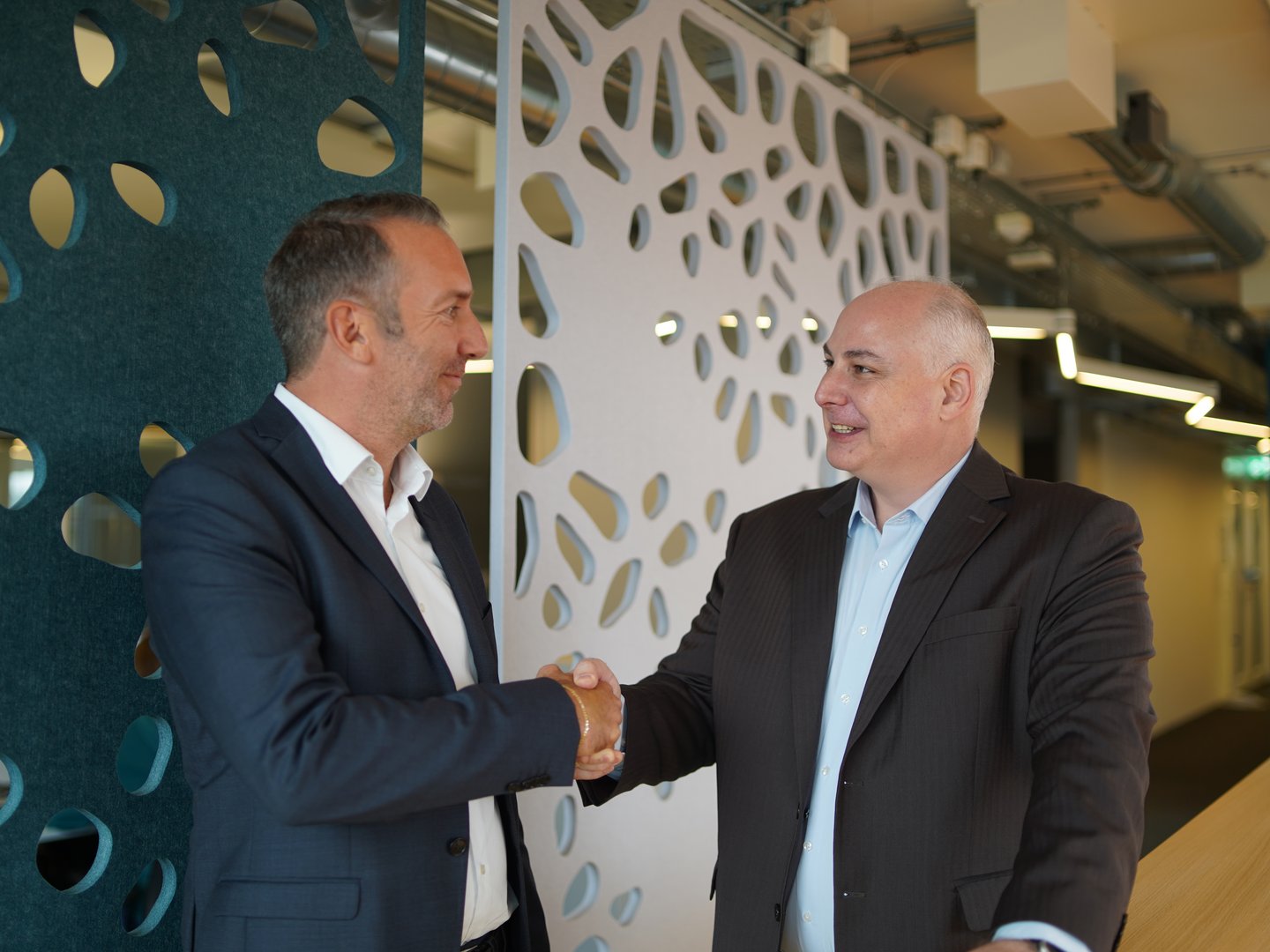 Roger Süess and Heiko Siats shaking hands in Green’s modern office.