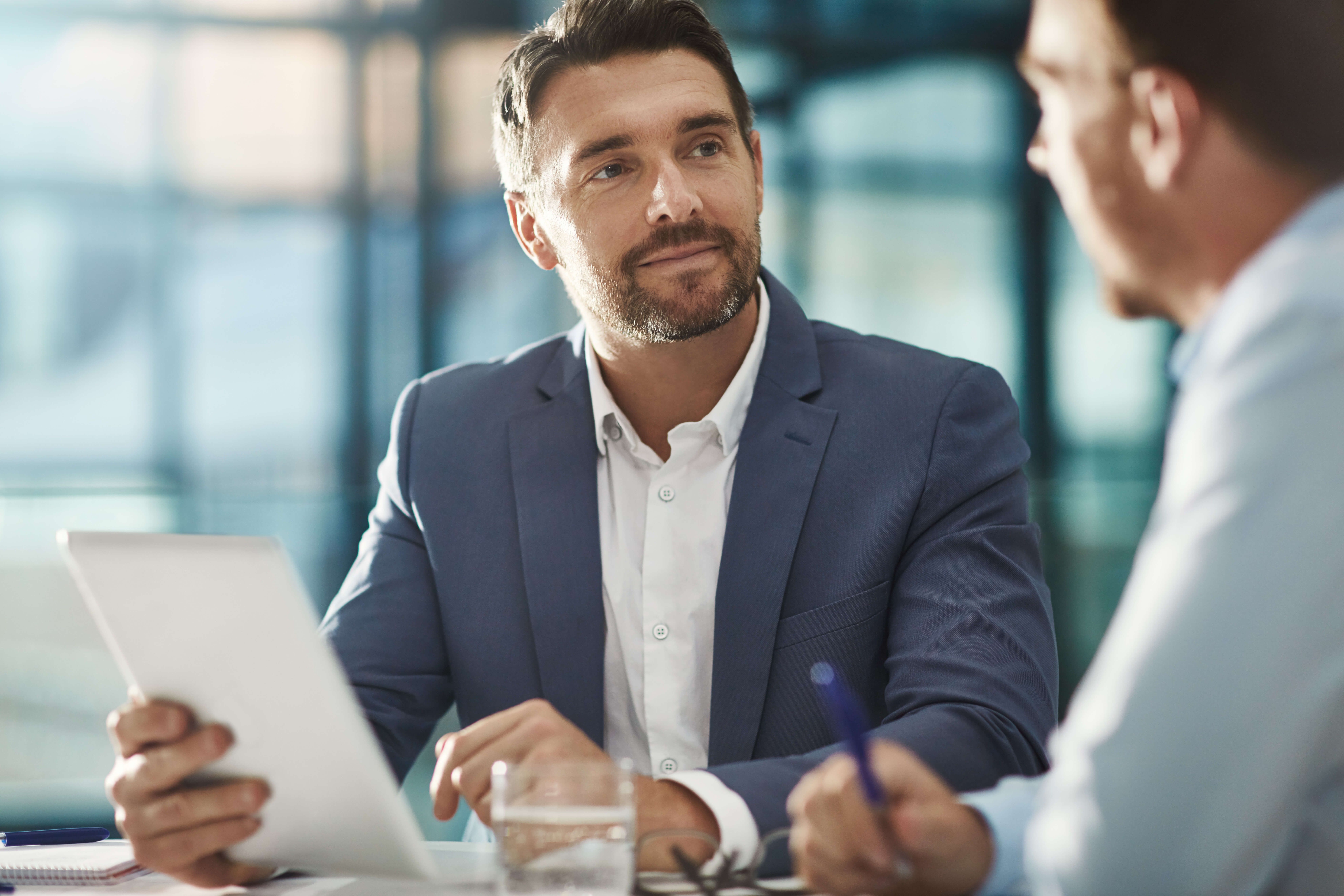Man in a suit listens to another man while talking