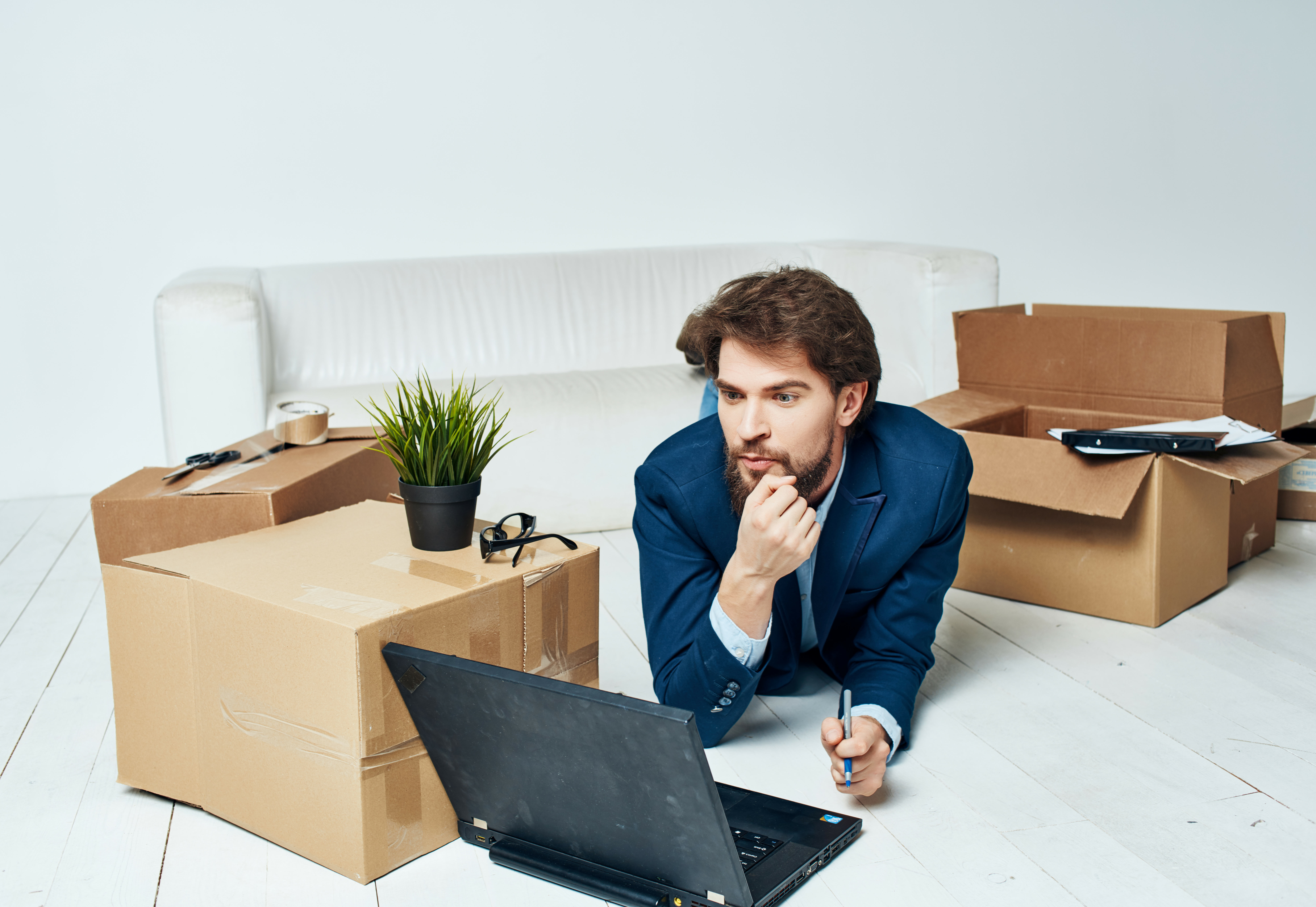 Man lies on the floor surrounded by moving boxes, thinking about how to quickly and securely transfer his domain to Green.