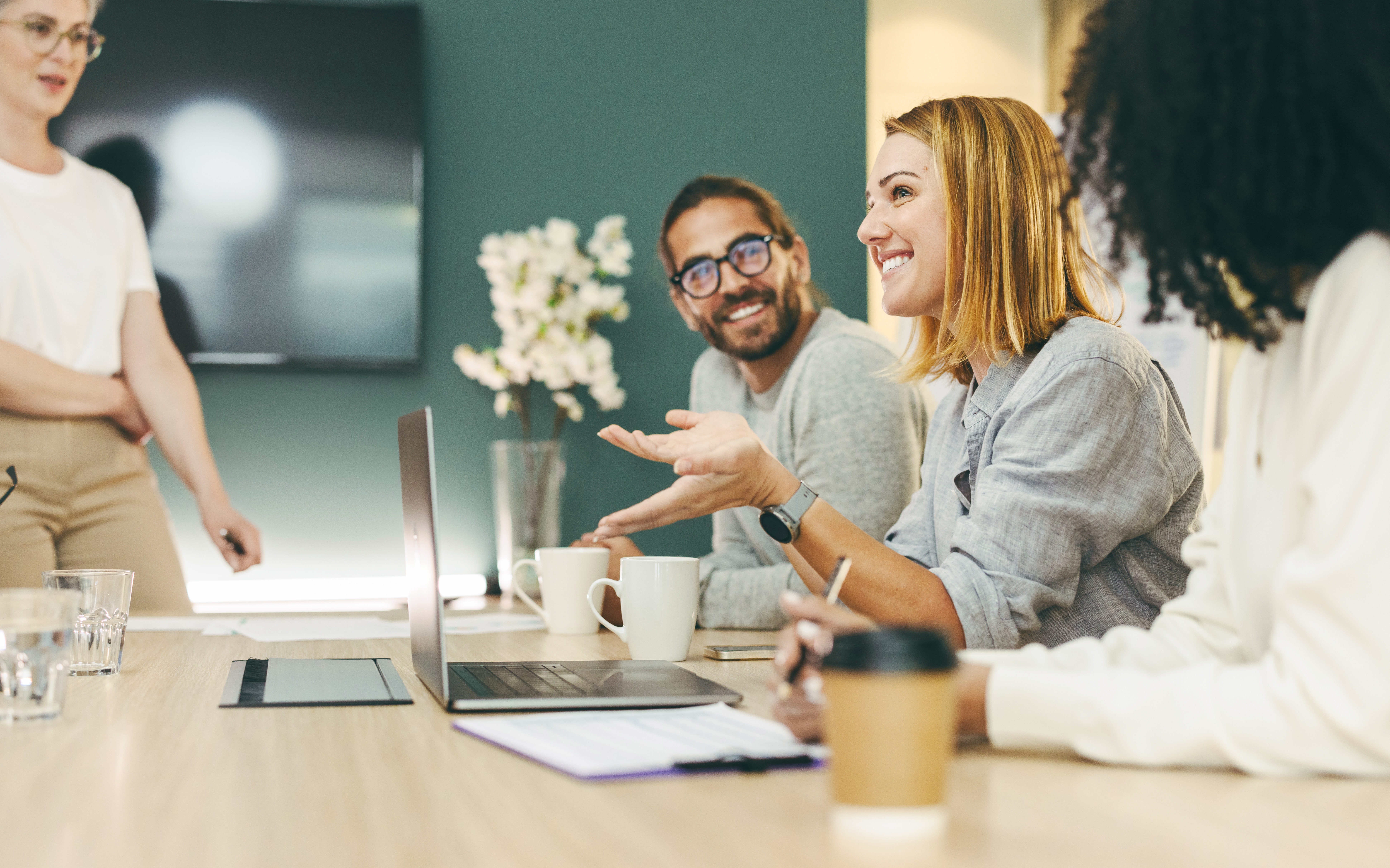 Vier zufriedene Personen an einem Schreibtisch im Gespräch