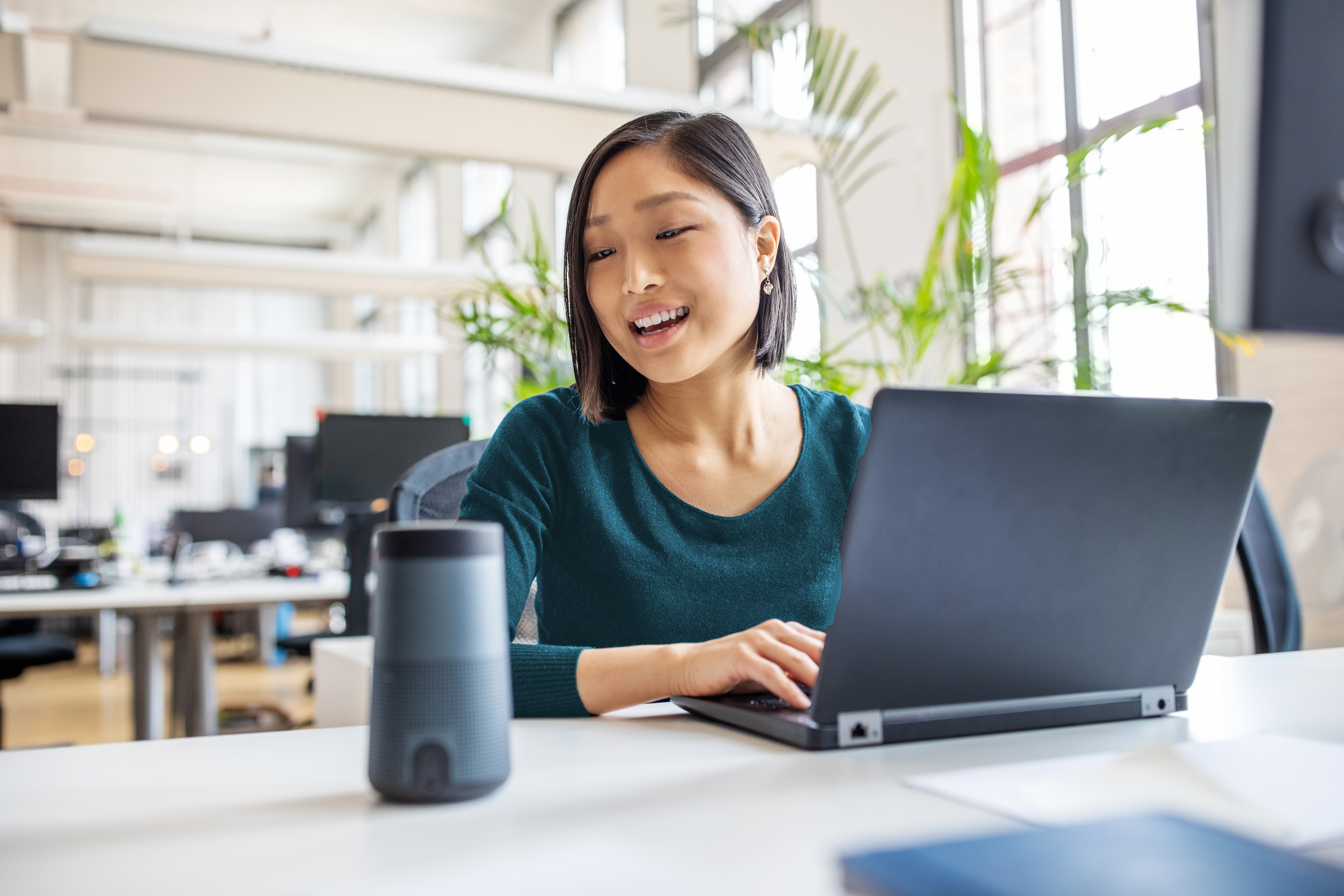 Une femme asiatique devant son ordinateur portable parle à Alexa