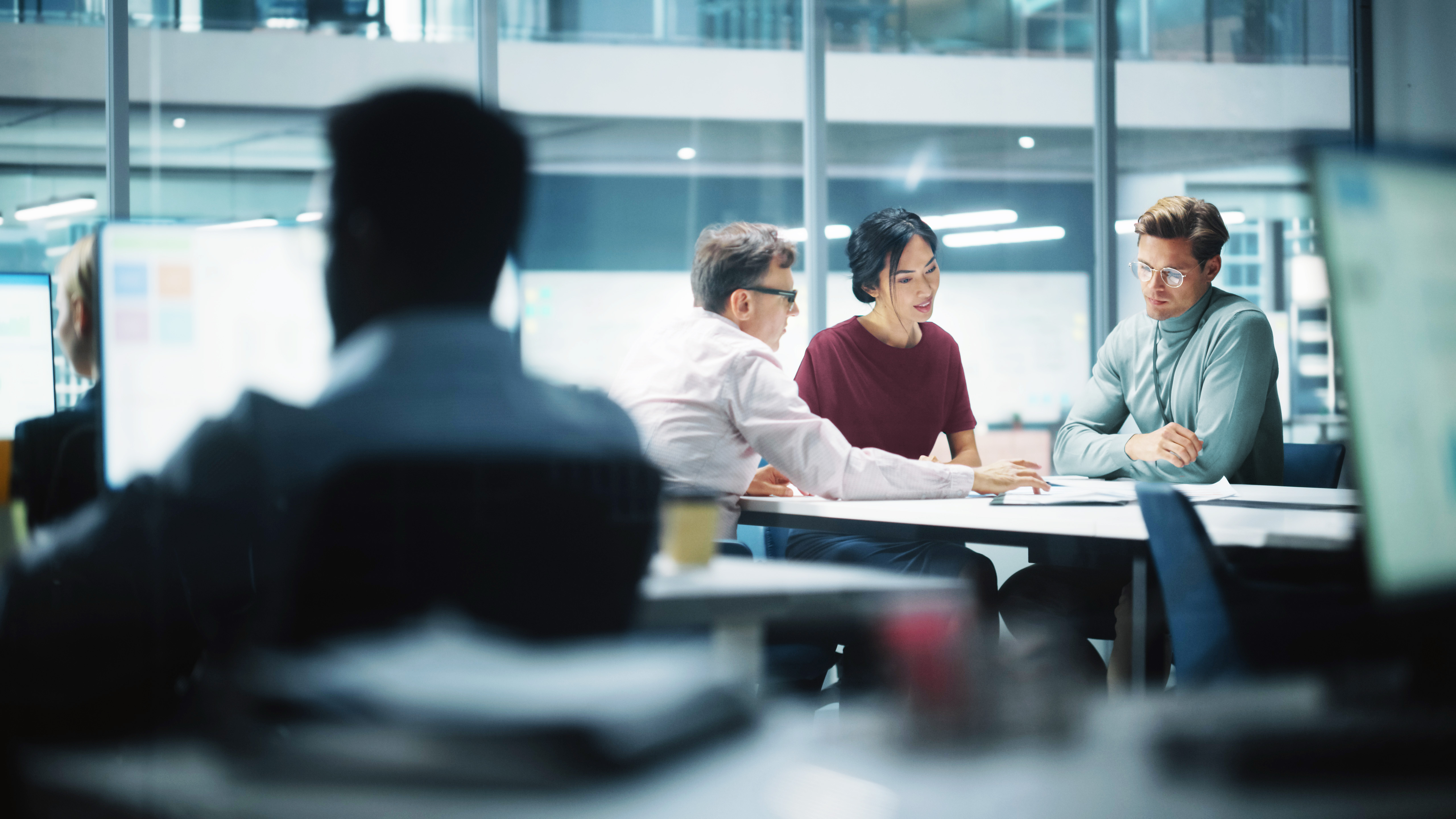 Zwei Männer und eine Frau an einem Tisch in einer Besprechung