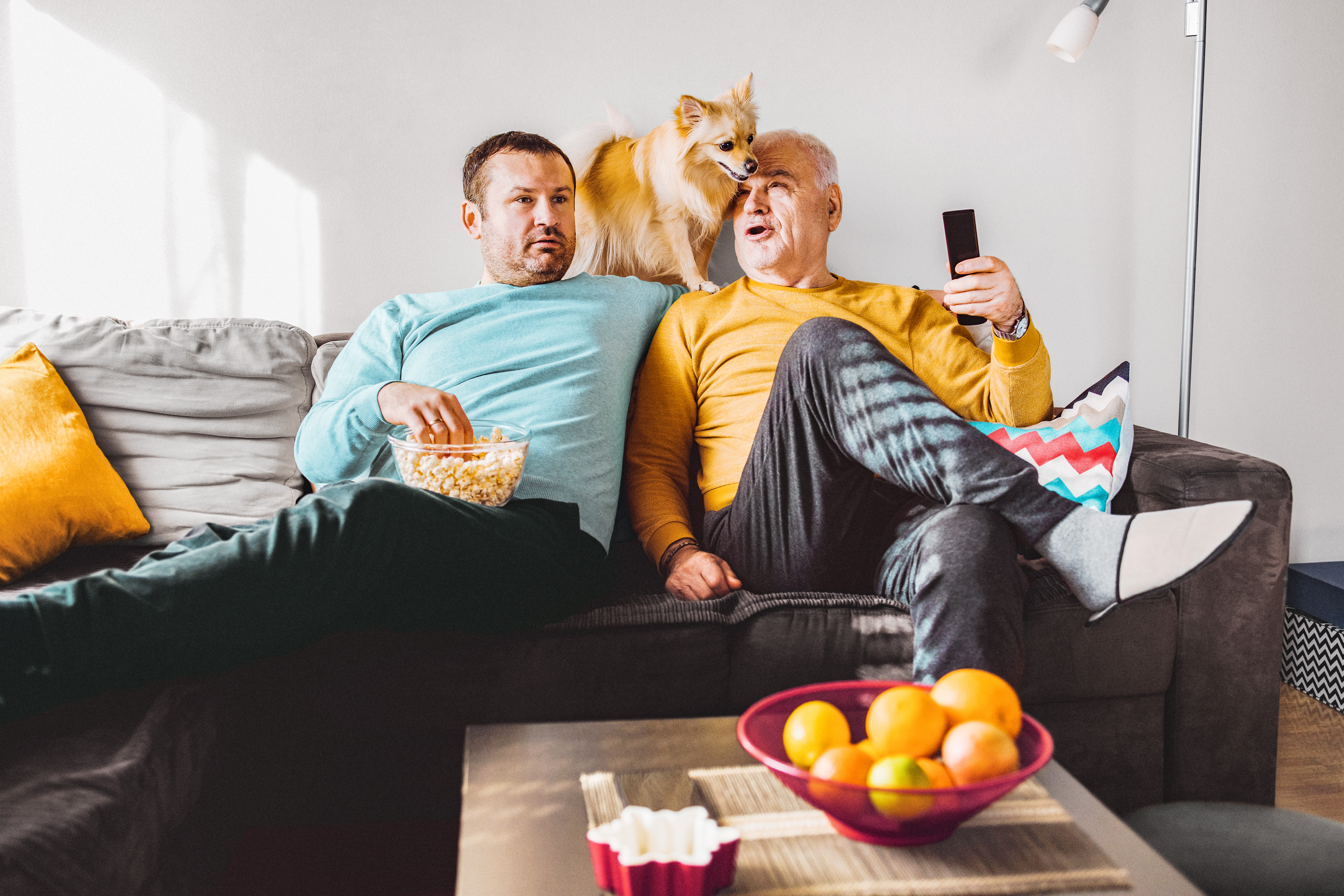 Two friends and their dog are watching TV together.