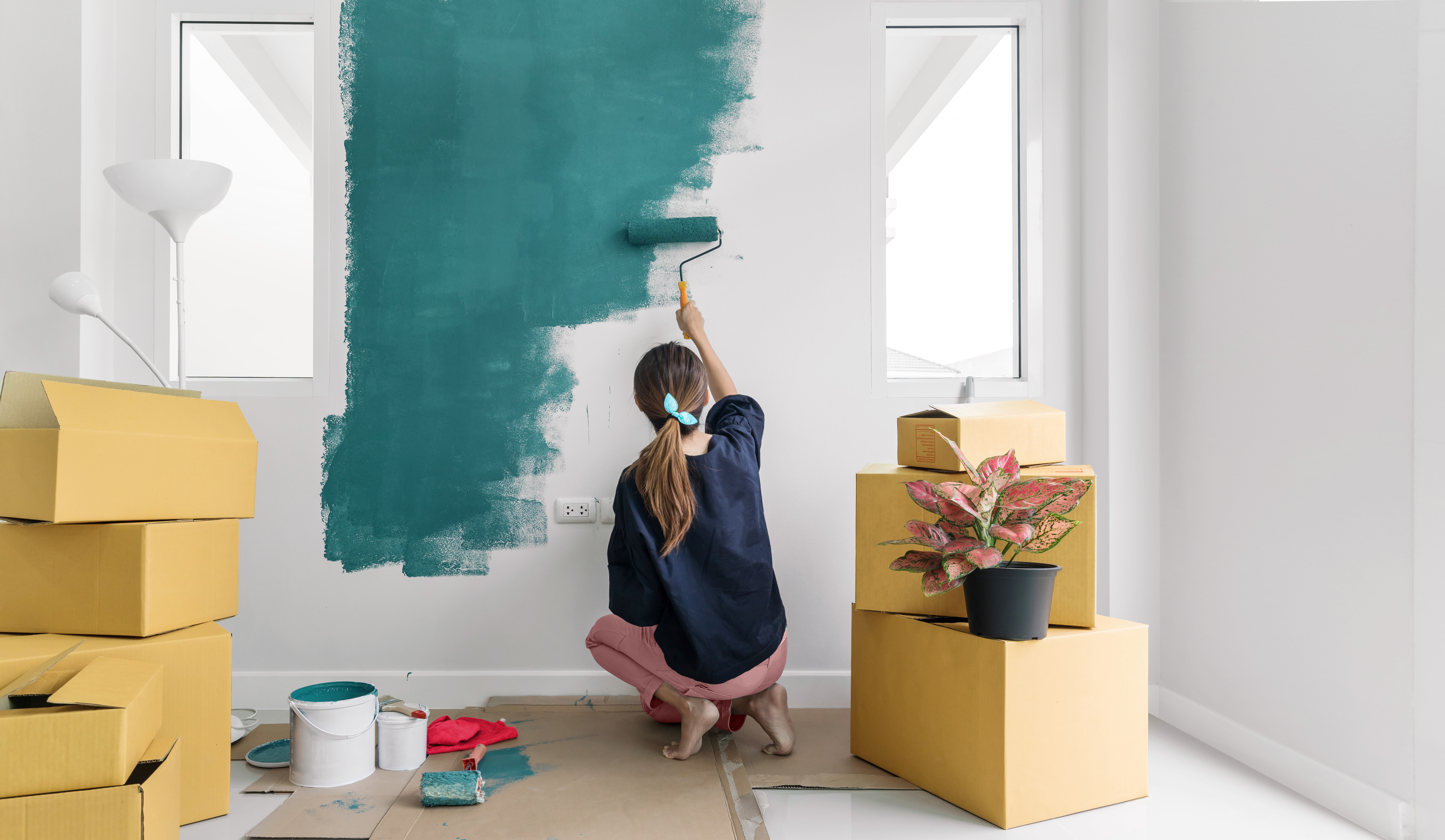 Frau beim Umzug streicht eine Wand in Green Farben