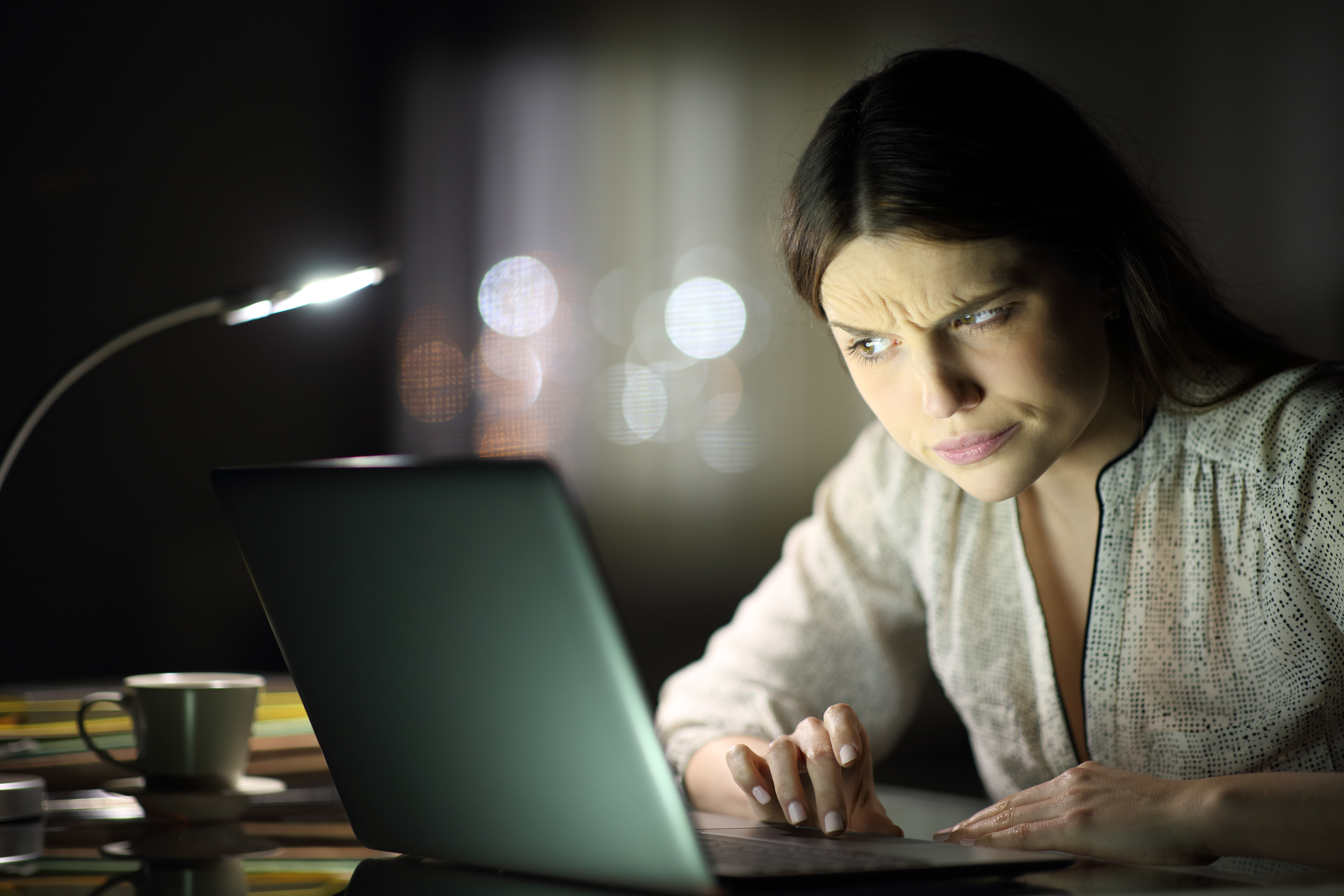 Frau überprüft verdächtige Phishing Nachrichten auf ihrem Laptop.